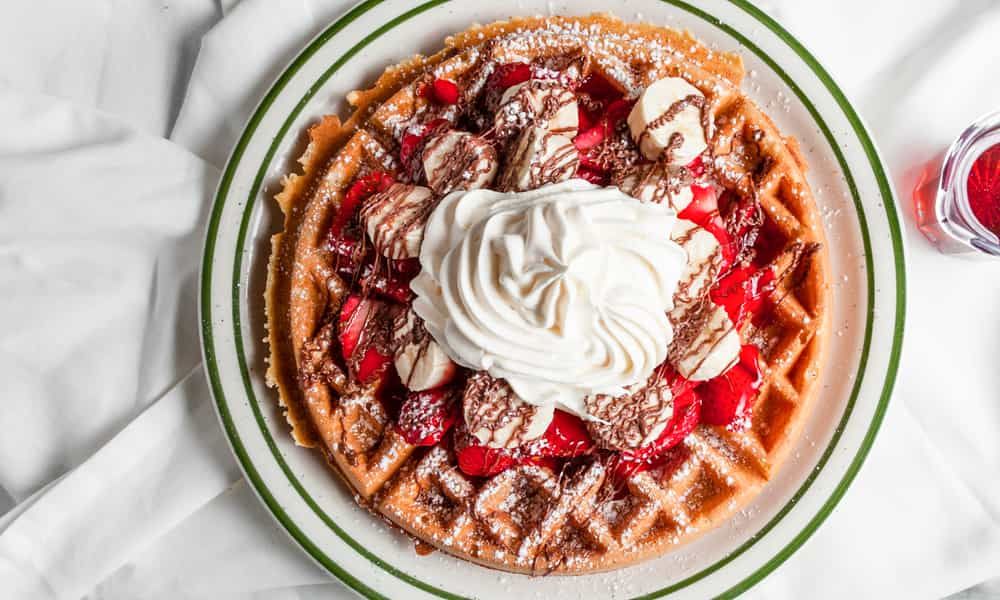 Made-fresh Belgian waffle topped with whipped cream and fresh fruit